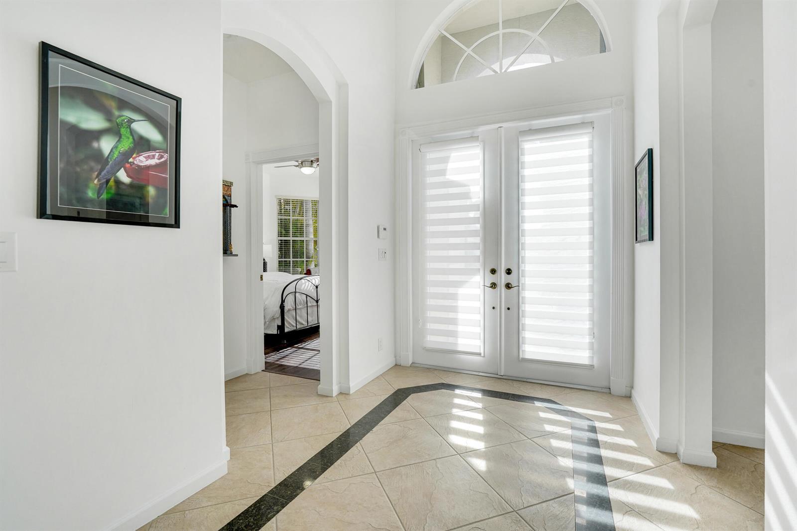 A bright entryway features white walls, tiled floors with a dark border, and double glass doors — 10916 Northgreen Drive, Lake Worth FL 33449, LAKE WORTH, FL