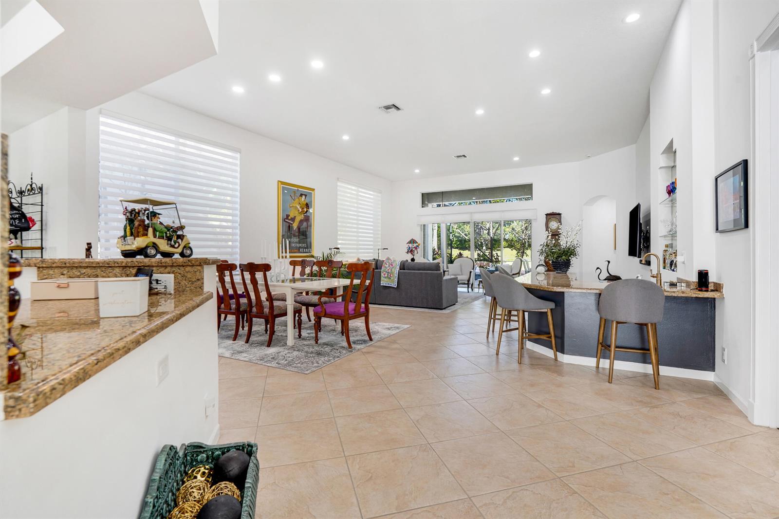 An open-concept living and dining area features tile flooring, a kitchen island, and large windows — 10916 Northgreen Drive, Lake Worth FL 33449, LAKE WORTH, FL