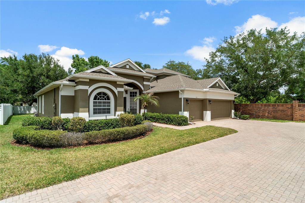 A one-story house with a tan stucco exterior, arched windows, and a three-car garage — 925 BAINBRIDGE LOOP, WINTER GARDEN, FL