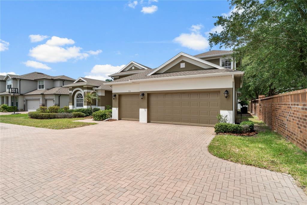 A single-story house with a tan exterior, arched window, and a paved driveway — 925 BAINBRIDGE LOOP, WINTER GARDEN, FL