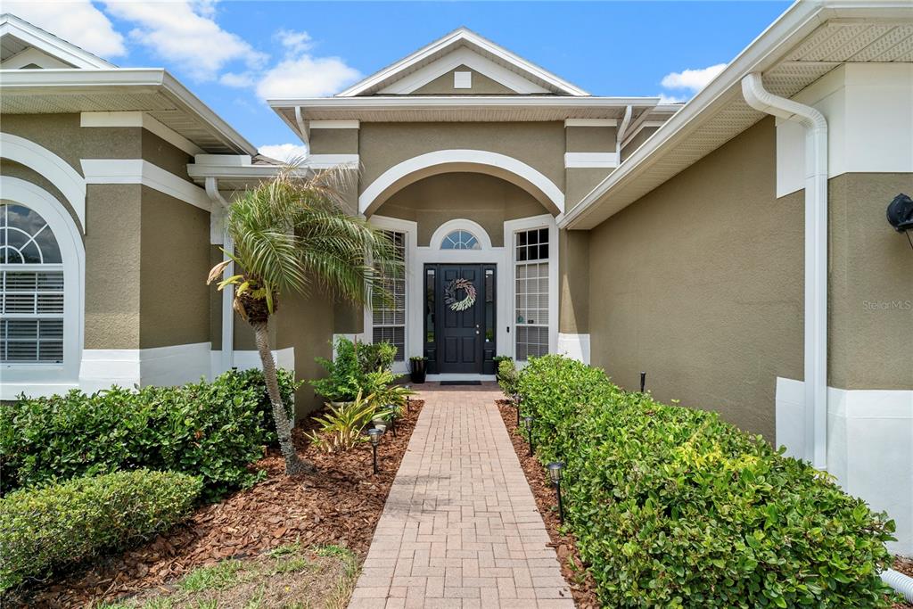 A two-story house with a three-car garage and a paved driveway under a blue sky — 925 BAINBRIDGE LOOP, WINTER GARDEN, FL