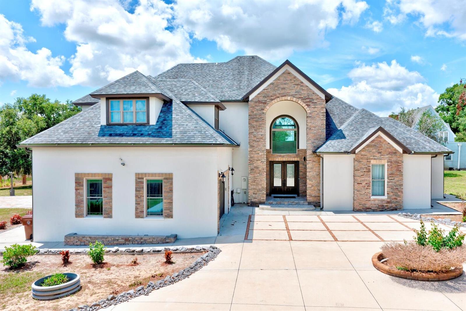 A two-story house with a stone facade, stucco walls, and a gray shingled roof — 91 Woodland Drive, FL 33844, FL