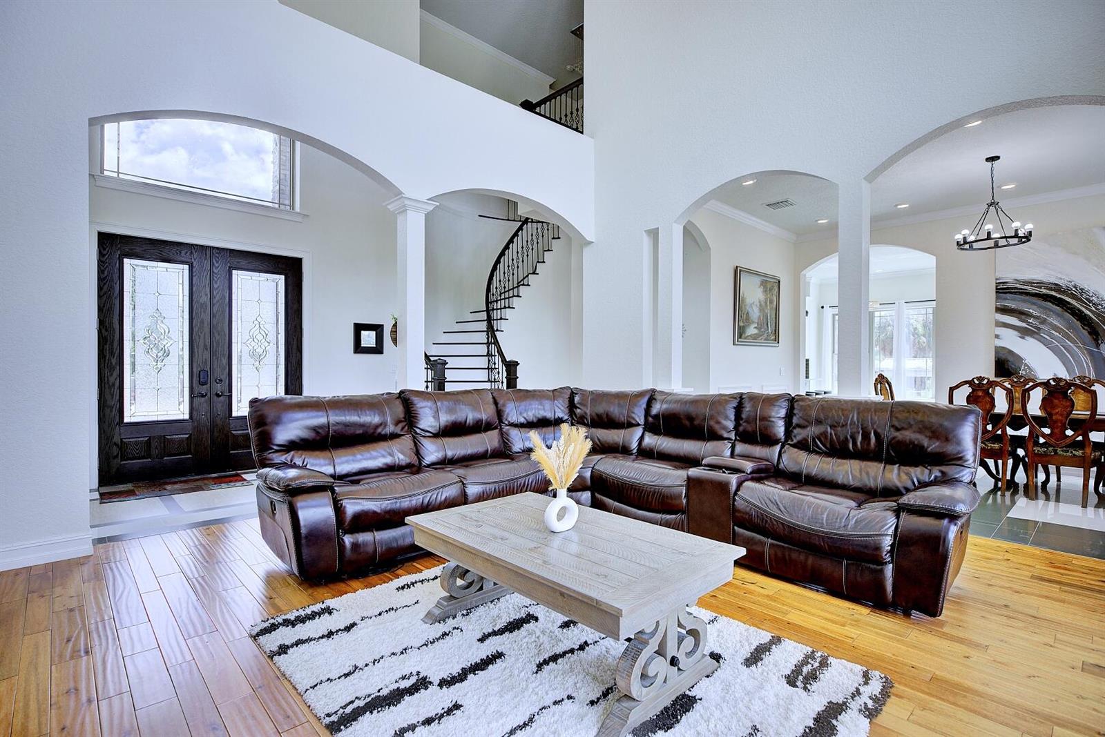 A spacious living room features a large brown leather sectional, a coffee table, and stairs — 91 Woodland Drive, FL 33844, FL
