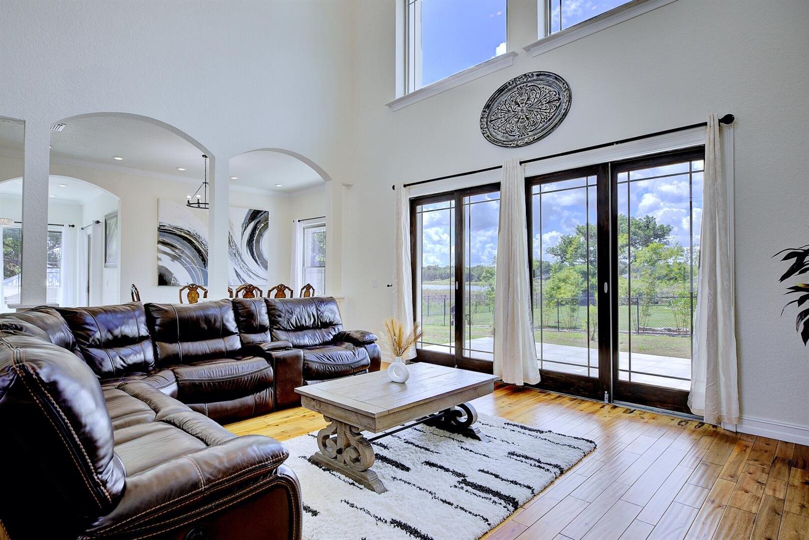 A living room features a leather sectional, wood coffee table, and large windows overlooking a yard — 91 Woodland Drive, FL 33844, FL