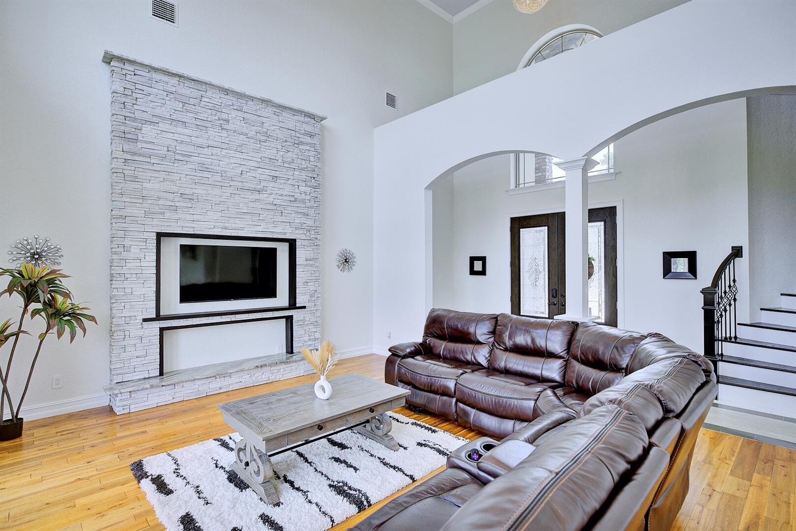 A living room features a stone fireplace with a built-in television, sectional sofa, and staircase — 91 Woodland Drive, FL 33844, FL
