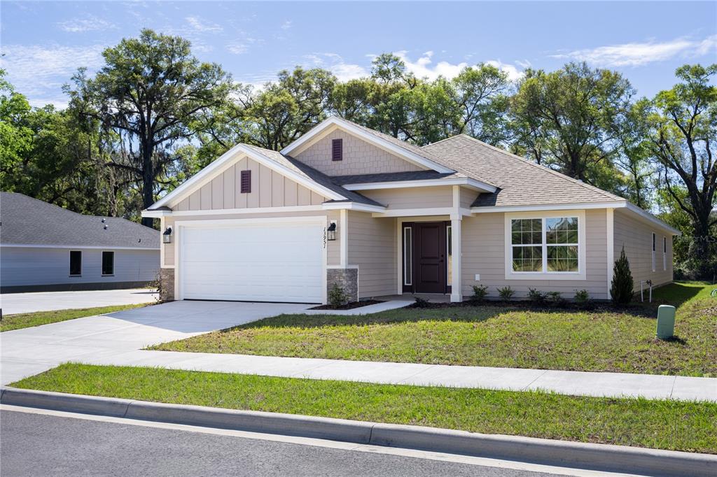 A single-story house with beige siding, a two-car garage, and a dark front door — 13646 NW 150TH CIRCLE, ALACHUA, FL