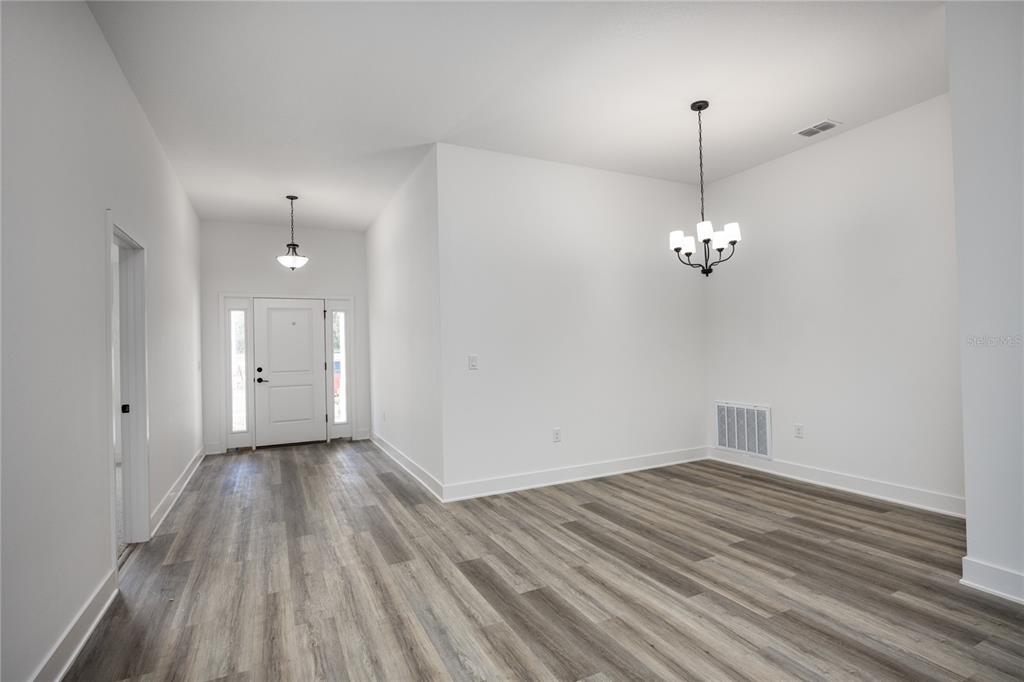 An entryway and dining area with white walls, gray wood-look flooring, and two light fixtures — 13646 NW 150TH CIRCLE, ALACHUA, FL