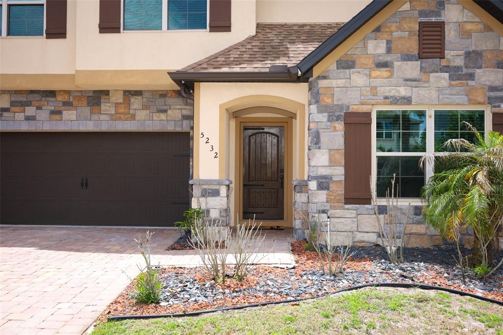 The exterior of a two-story home features a stone facade, brown garage, and front door — 5232 VILLA ROSA AVENUE, ST CLOUD, FL