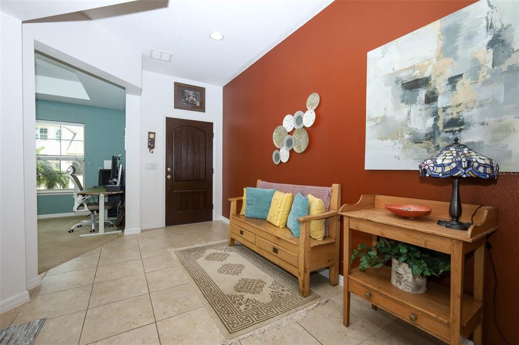 An entryway features a wooden bench, a side table with a lamp, and a rust-colored wall — 5232 VILLA ROSA AVENUE, ST CLOUD, FL