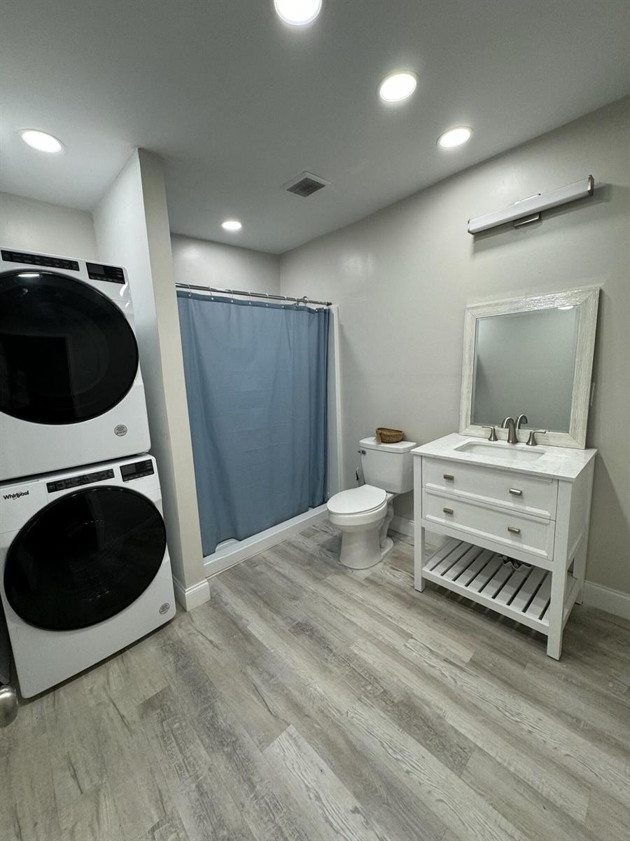 A bathroom features a stacked washer and dryer, a vanity, a toilet, and a shower — 4679 SE Ebbtide Avenue # O, Stuart FL 34997, STUART, FL