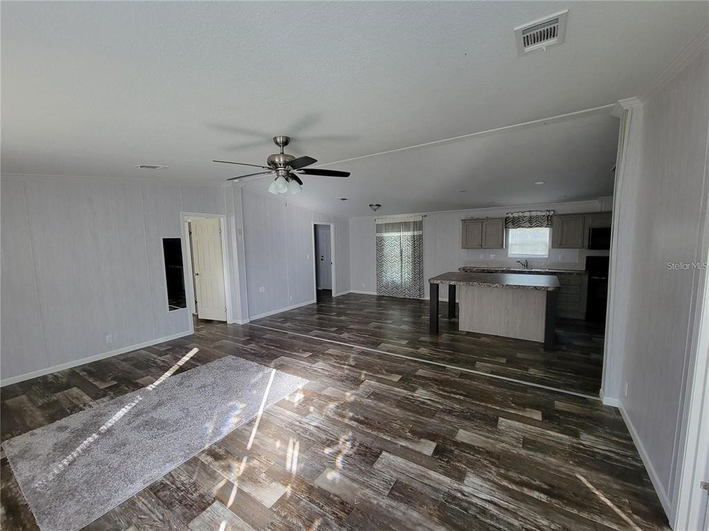 An open-concept living room and kitchen featuring wood-look flooring and a central island — 16625 SE 102ND AVENUE ROAD, SUMMERFIELD, FL