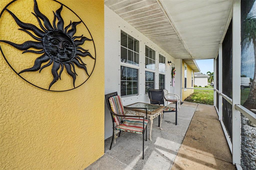 A screened-in porch features a yellow wall with a sun decoration and patio furniture — 316 SW 19TH TERRACE, CAPE CORAL, FL