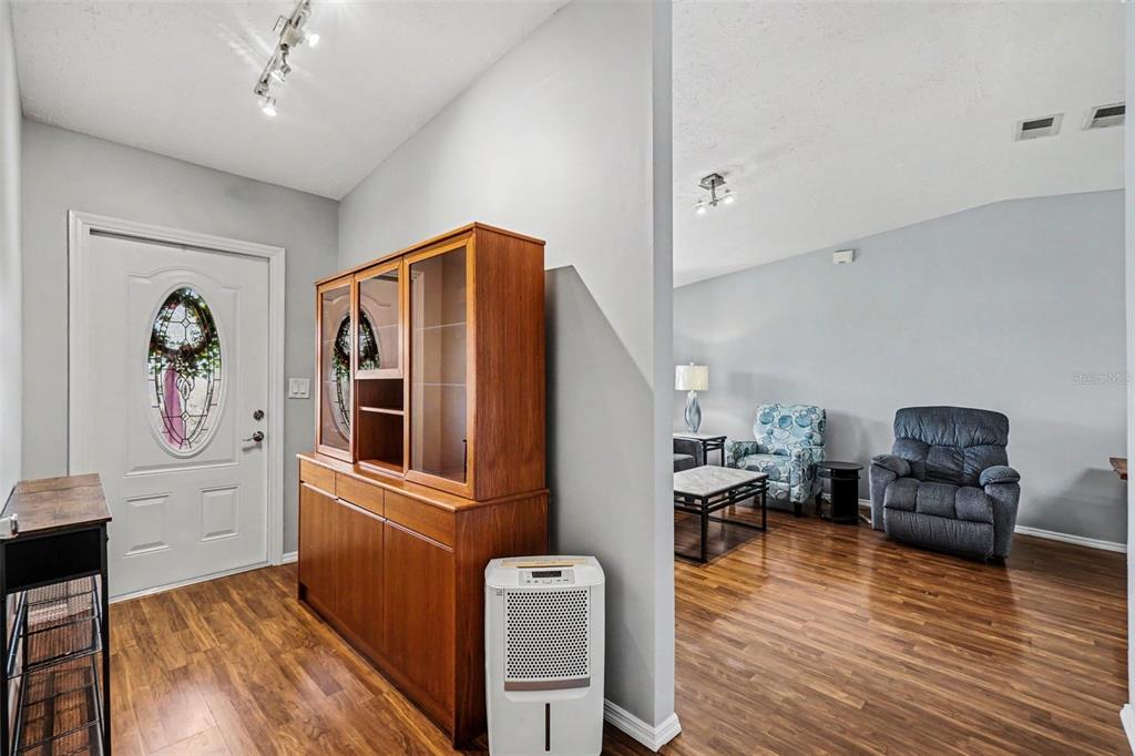 An entryway with wood flooring and a wooden hutch leads into a living room area — 316 SW 19TH TERRACE, CAPE CORAL, FL