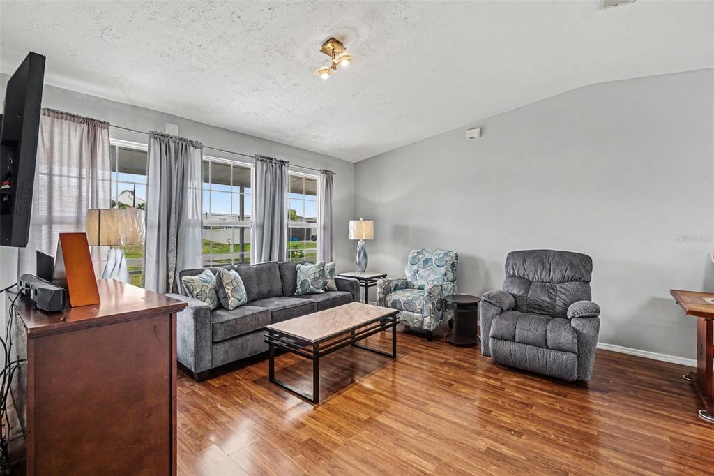 A living room features gray walls, hardwood flooring, a sofa, and a recliner — 316 SW 19TH TERRACE, CAPE CORAL, FL