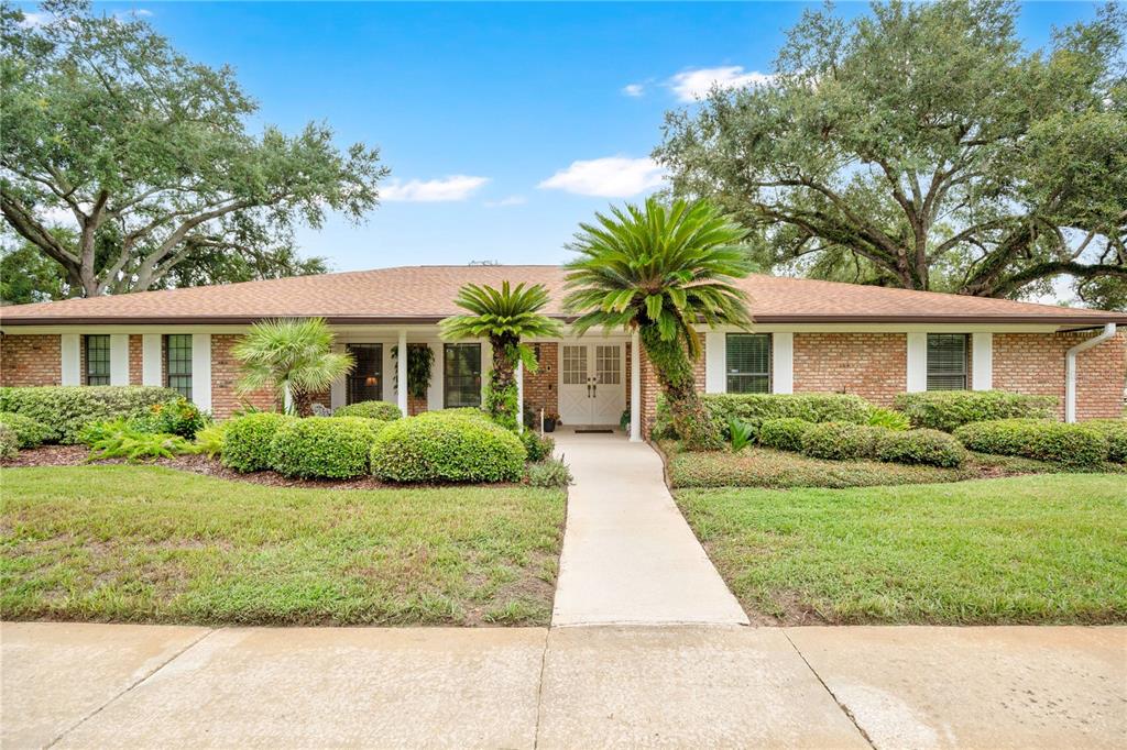 A single-story brick house features a walkway leading to double front doors and palm trees — 231 WHITE OAK CIRCLE, MAITLAND, FL