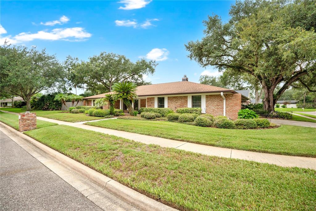 A single-story brick house with a hip roof sits on a corner lot with landscaping — 231 WHITE OAK CIRCLE, MAITLAND, FL