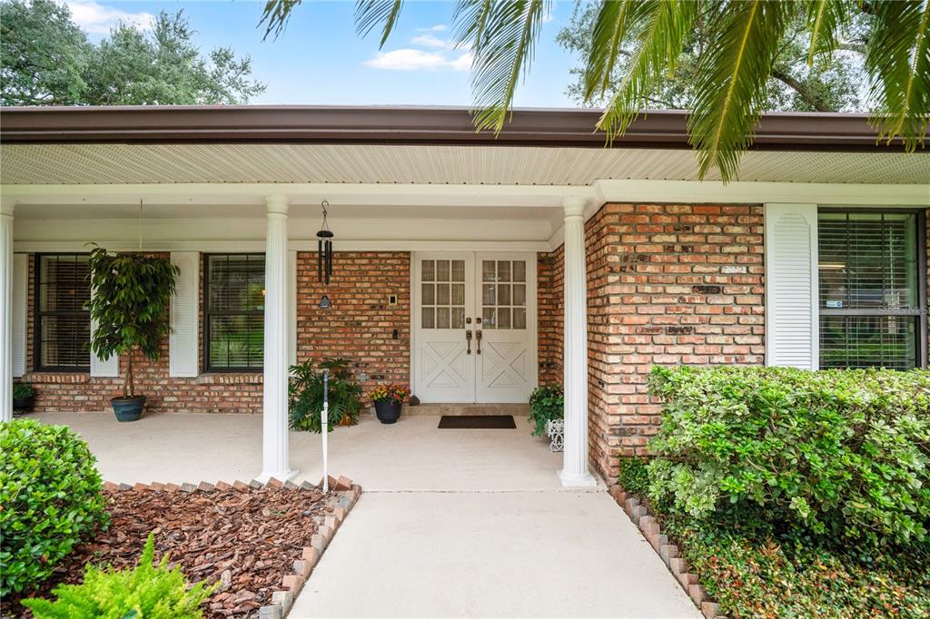 A brick exterior home features a covered front porch with white columns and double doors — 231 WHITE OAK CIRCLE, MAITLAND, FL