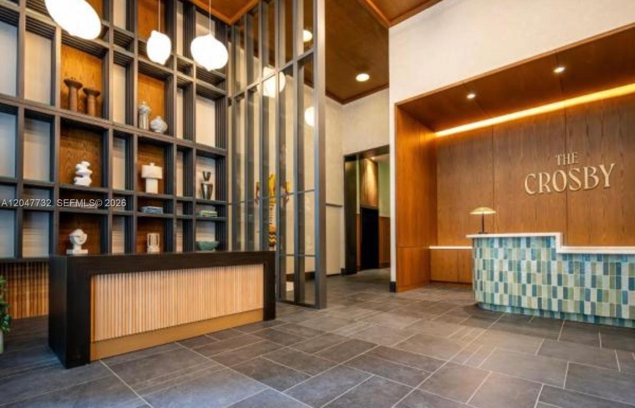 A modern lobby features a reception desk, a tall wood-paneled wall, and built-in shelving — 11 NE 6th St # 213, Miami FL 33132, MIAMI, FL
