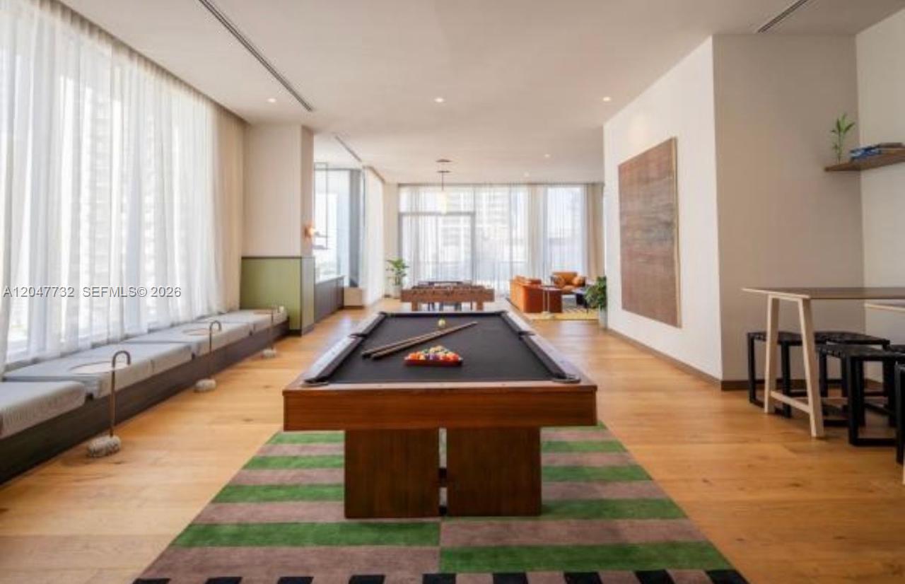 A spacious game room features a pool table, wood flooring, and floor-to-ceiling windows — 11 NE 6th St # 213, Miami FL 33132, MIAMI, FL