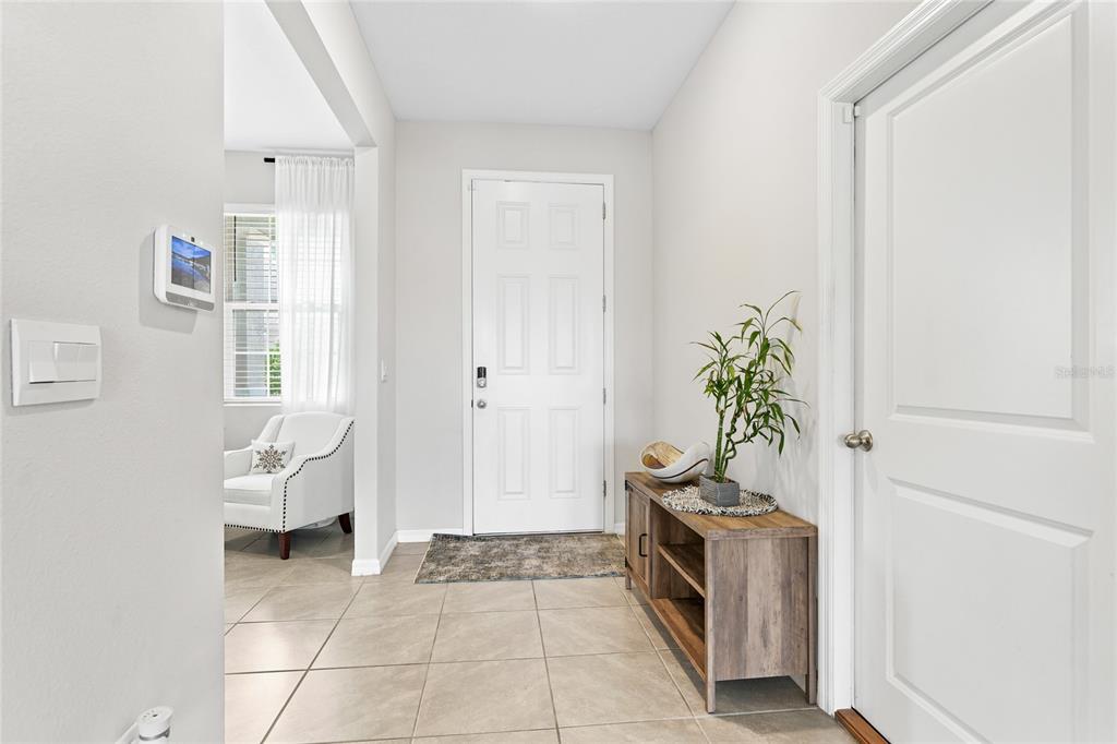 A bright entryway features light tile flooring, a white front door, and a wooden console table — 5603 NIGHT OWL TERRACE, PALMETTO, FL