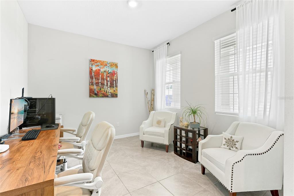 A home office features a long wooden desk, two white chairs, and two armchairs — 5603 NIGHT OWL TERRACE, PALMETTO, FL
