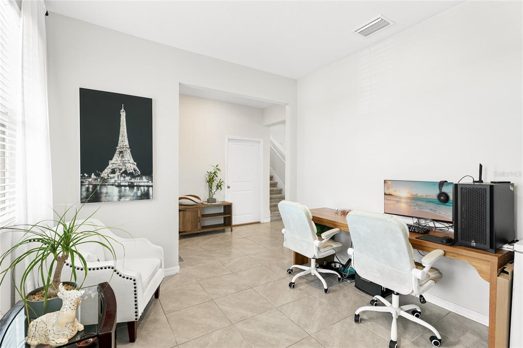 A home office features a dual-desk setup, white chairs, tile flooring, and a framed Eiffel Tower print — 5603 NIGHT OWL TERRACE, PALMETTO, FL