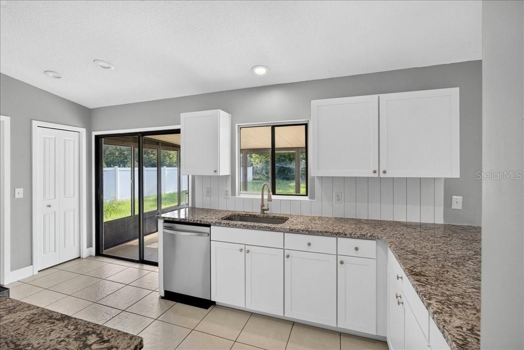 A kitchen with white cabinets, granite countertops, a stainless steel dishwasher, and a sliding door — 40 BOULDER ROCK DRIVE, PALM COAST, FL