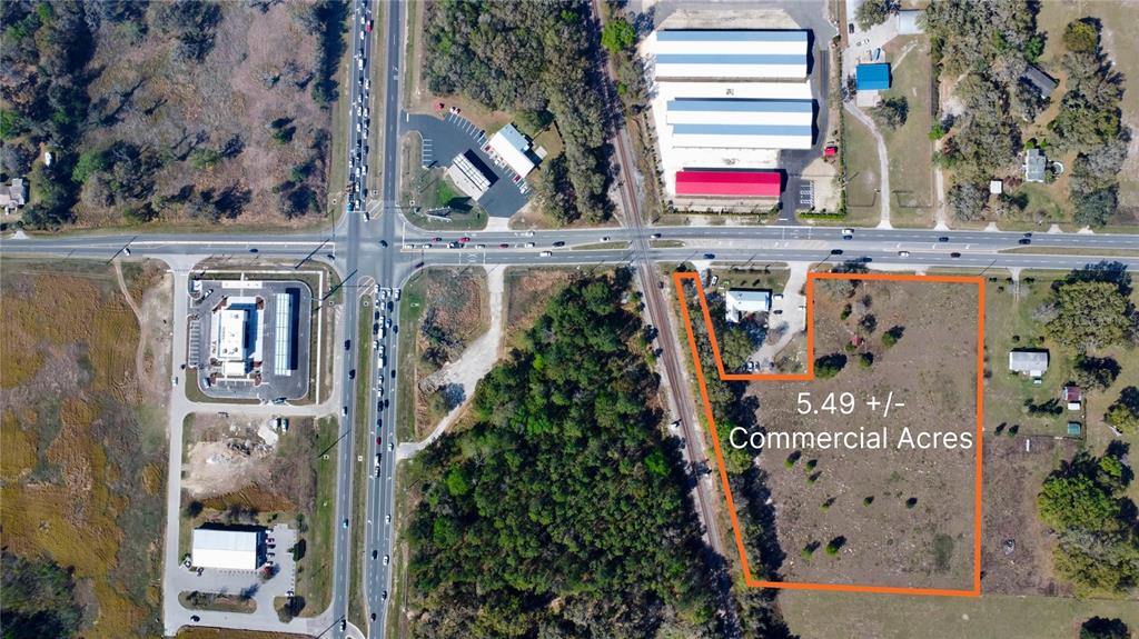 This aerial map shows a 5.49-acre commercial plot outlined in orange near a road intersection — 6910 SE HIGHWAY 42, SUMMERFIELD, FL