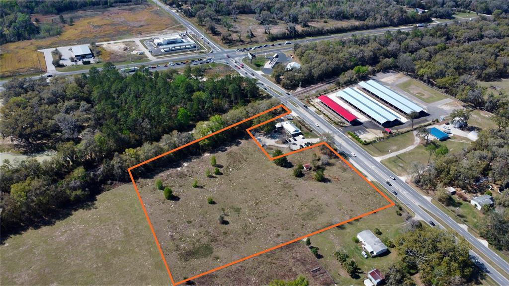 An aerial view shows a large, vacant, irregularly shaped lot outlined in orange near a road — 6910 SE HIGHWAY 42, SUMMERFIELD, FL