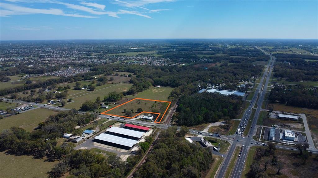 An aerial view shows a rectangular plot of land outlined in orange near a highway — 6910 SE HIGHWAY 42, SUMMERFIELD, FL