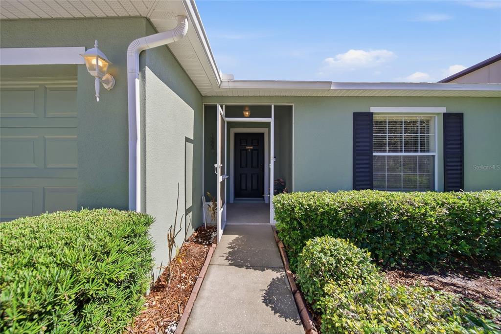 The exterior of a house features a green facade, a walkway, and a front door — 30837 SONNET GLEN DRIVE, WESLEY CHAPEL, FL