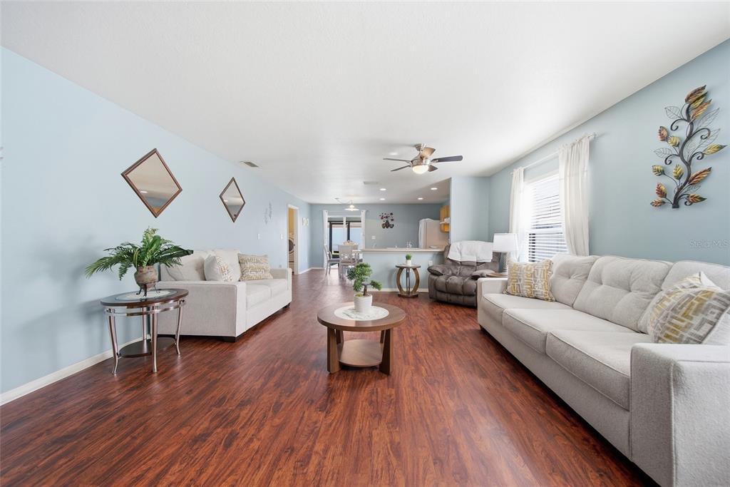 A living room with light blue walls, wood-look flooring, and two light-colored sofas — 30837 SONNET GLEN DRIVE, WESLEY CHAPEL, FL