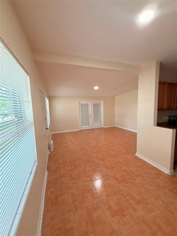 An interior view shows a room with orange tile flooring, white walls, and glass doors — 1503 W LINEBAUGH AVENUE, TAMPA, FL