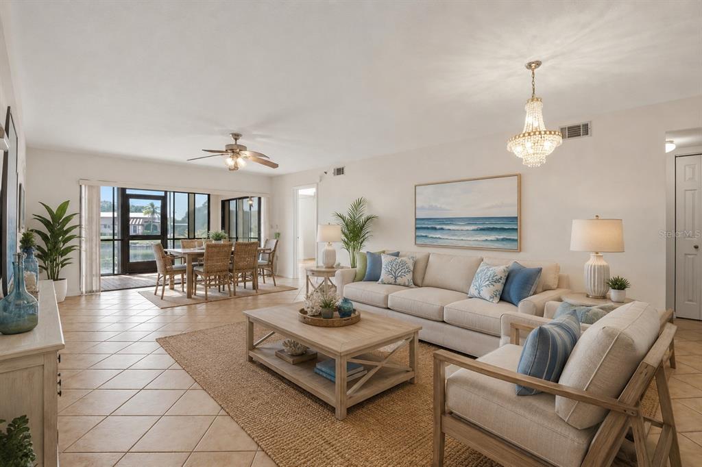 A bright living and dining area features tile floors, a neutral sofa, and a chandelier — 23465 HARBORVIEW ROAD UNIT 913, PUNTA GORDA, FL