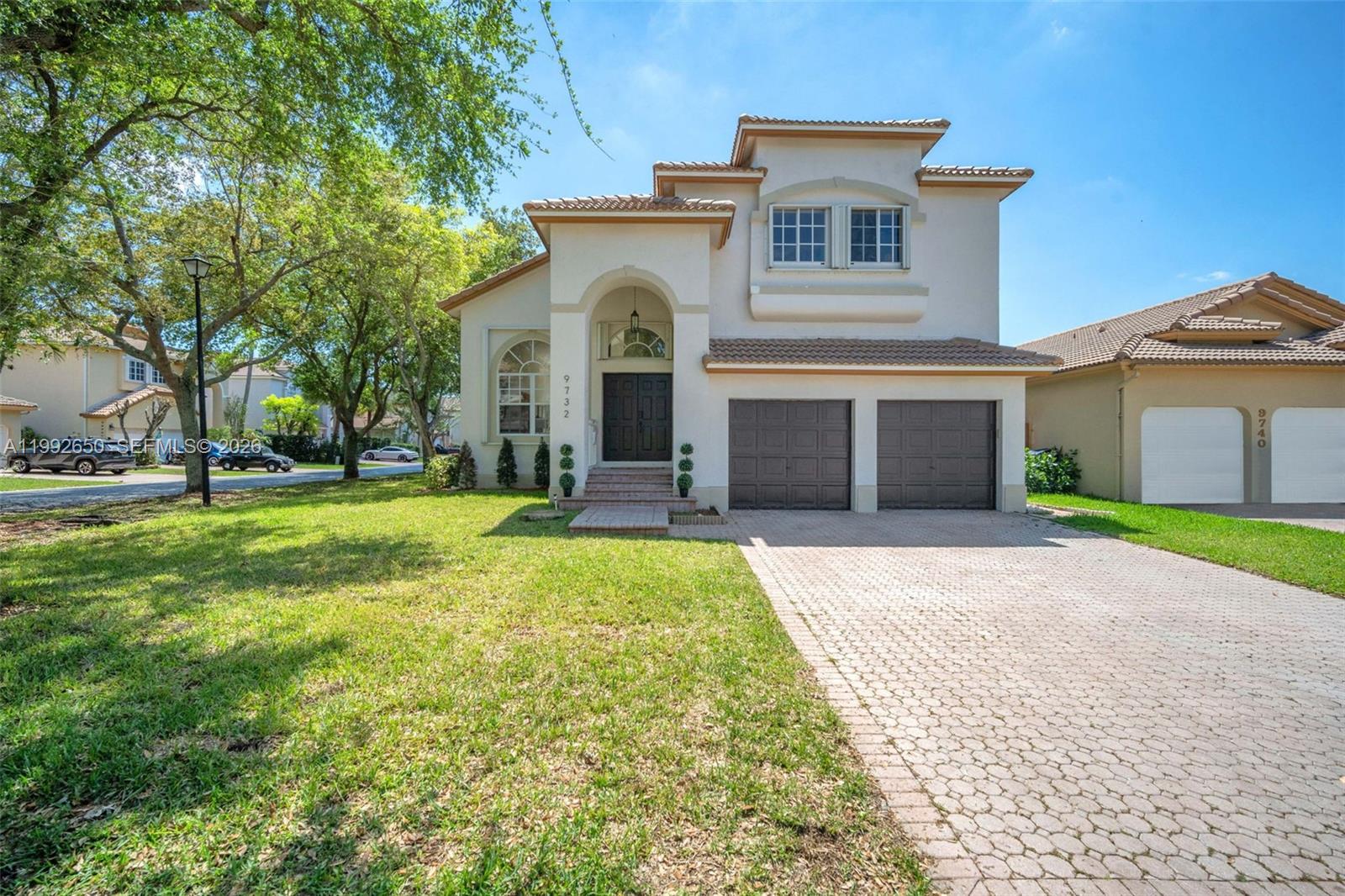 A two-story house with a beige stucco exterior, a tiled roof, and a paved driveway — 9732 NW 32nd St, Doral FL 33172, DORAL, FL