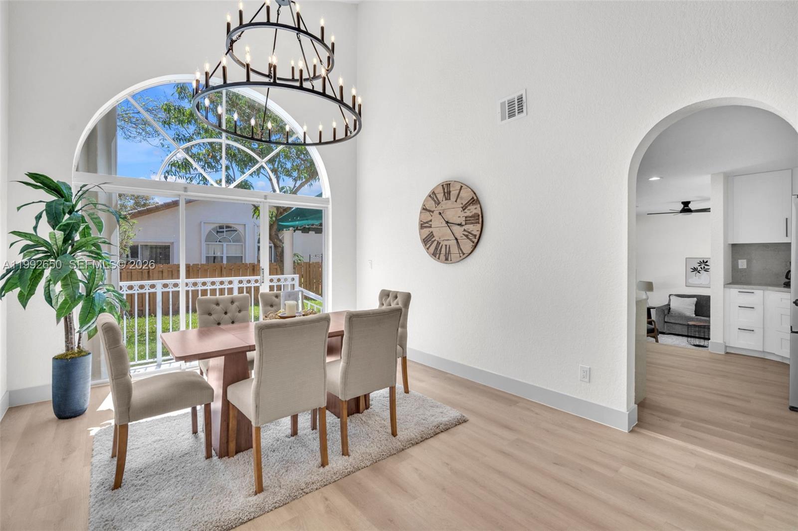A dining room features a large arched window, a chandelier, and a wooden table set — 9732 NW 32nd St, Doral FL 33172, DORAL, FL