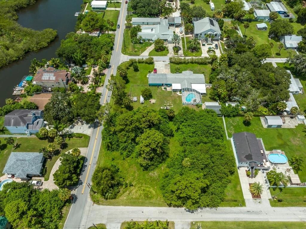 An aerial view shows a residential property with a house, pool, and large wooded lot — 6307 OELSNER STREET UNIT 11&12, NEW PORT RICHEY, FL