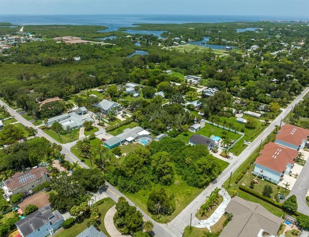 An aerial view shows a residential neighborhood with houses, swimming pools, and dense green trees — 6307 OELSNER STREET UNIT 11&12, NEW PORT RICHEY, FL