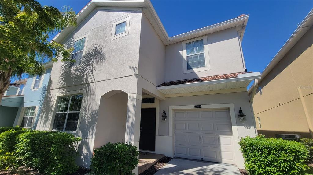 A two-story house with a beige stucco exterior, a single-car garage, and green landscaping — 2952 BEACH PALM AVENUE, KISSIMMEE, FL