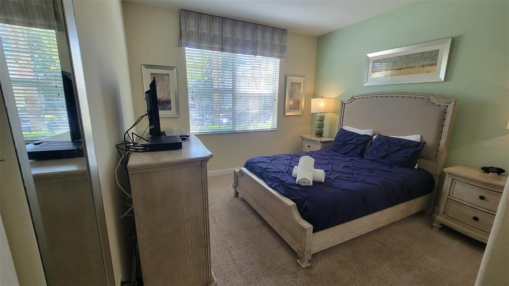 A bedroom features a bed with a blue comforter, a dresser, and a window — 2952 BEACH PALM AVENUE, KISSIMMEE, FL