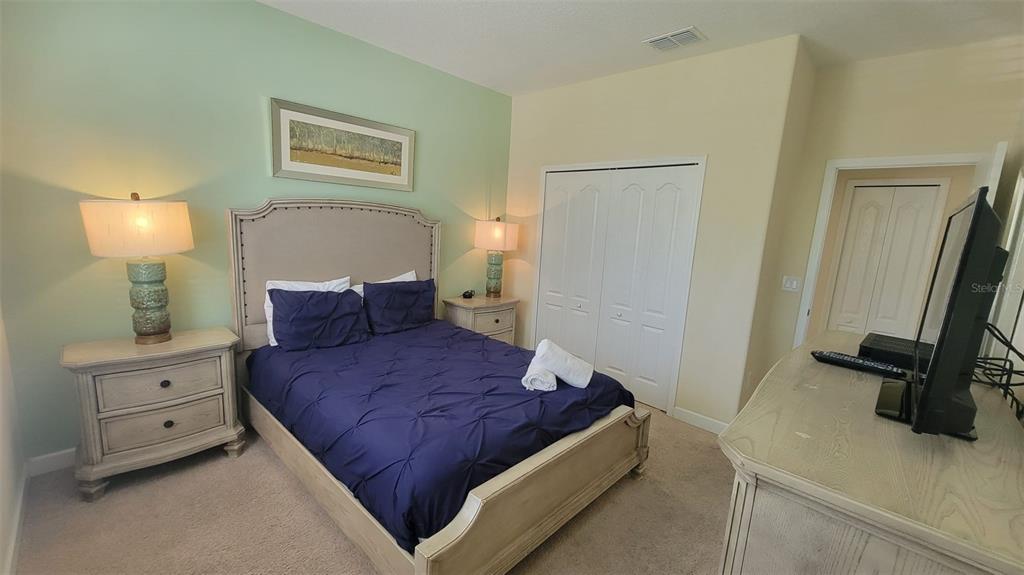 A bedroom features a bed with a blue comforter, two nightstands, and a dresser — 2952 BEACH PALM AVENUE, KISSIMMEE, FL