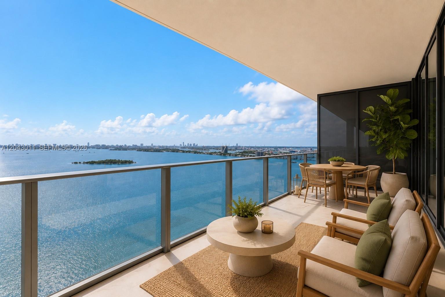 A balcony with outdoor seating overlooks a large body of water and a distant city skyline — 700 NE 24 ST # 1004, Miami FL 33137, MIAMI, FL
