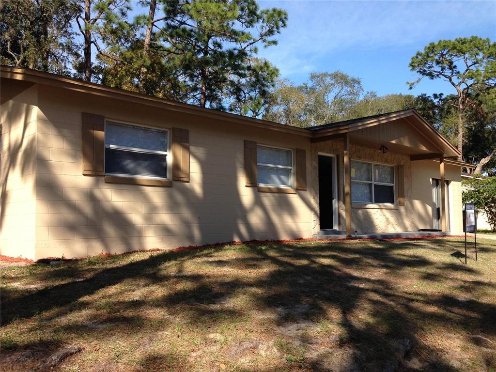 A single-story beige house with a concrete block exterior and a covered front porch — 3650 TRIANON DRIVE, ORLANDO, FL