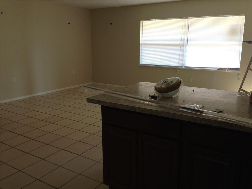 A kitchen island with a dark wood base sits in front of a tiled living area — 3650 TRIANON DRIVE, ORLANDO, FL