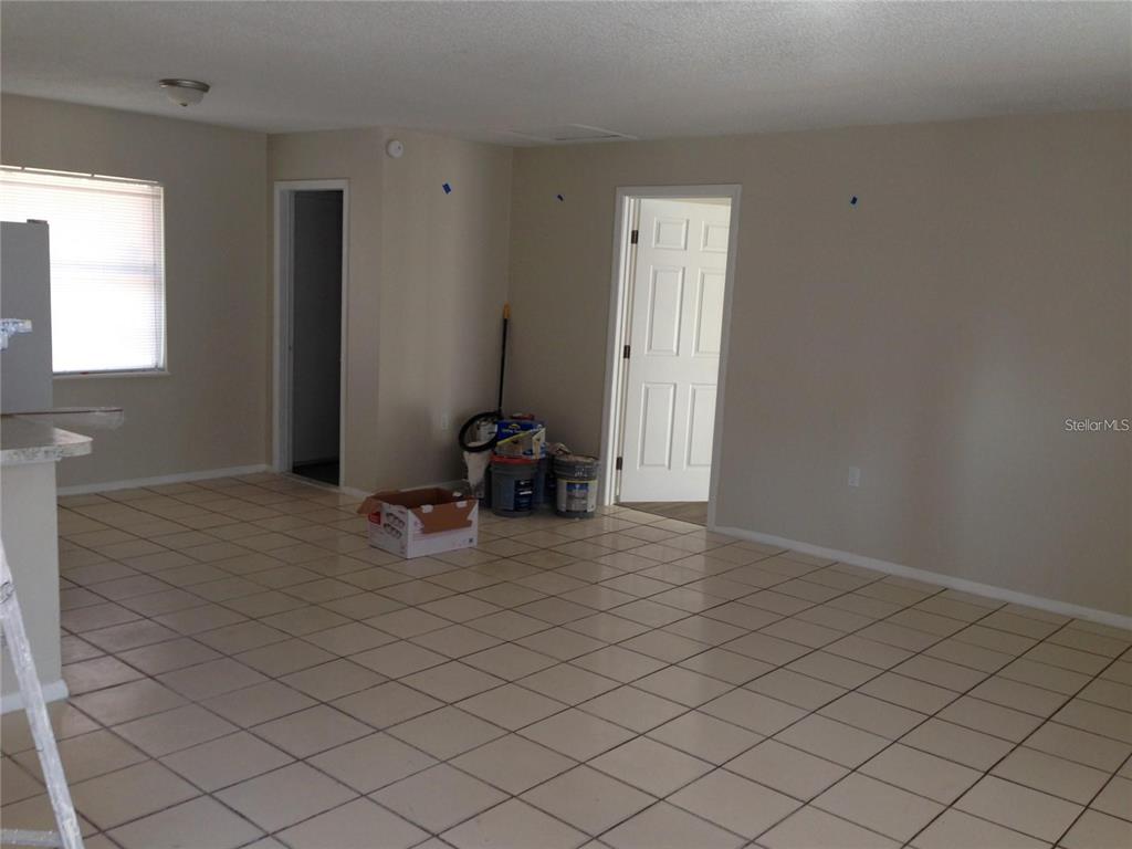 An interior view of a room with beige tile flooring, light-colored walls, and two doorways — 3650 TRIANON DRIVE, ORLANDO, FL