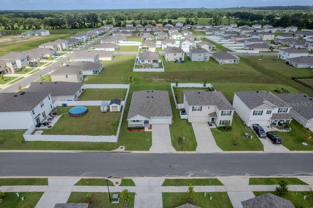 An aerial view shows a suburban neighborhood with single-family homes, driveways, and fenced backyards — 17070 NW 176TH WAY, ALACHUA, FL