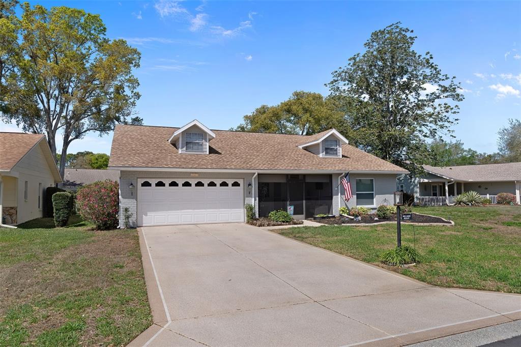 A single-story house with a white garage, gray brick exterior, and two dormer windows — 2323 WESTCHESTER BOULEVARD, SPRING HILL, FL