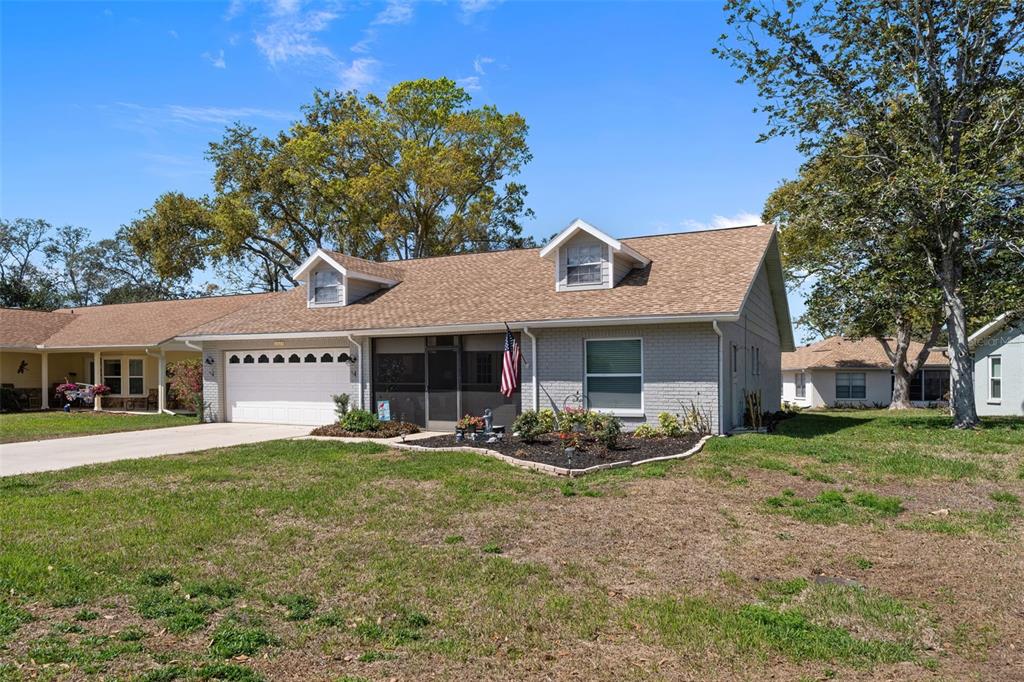 A single-story gray brick house with a two-car garage and a screened front entryway — 2323 WESTCHESTER BOULEVARD, SPRING HILL, FL