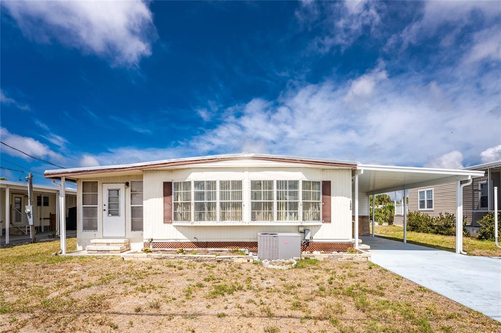A single-story manufactured home with a white exterior, a carport, and a front lawn — 1380 SEAGULL DRIVE, ENGLEWOOD, FL