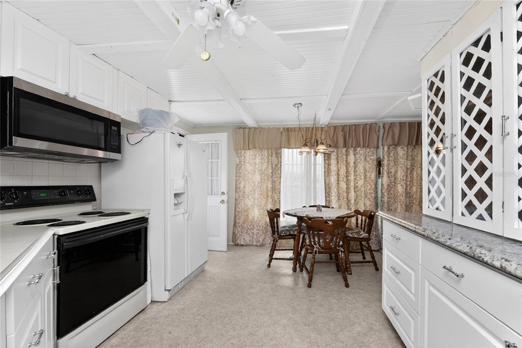 A kitchen with white cabinets, stainless steel appliances, and a small dining table with chairs — 1380 SEAGULL DRIVE, ENGLEWOOD, FL